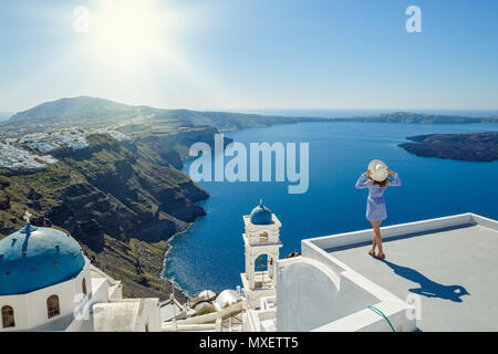 Giovane donna sorge su di una collina e guarda il paesaggio marino di Santorini, Grecia Foto Stock