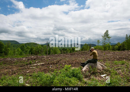 Triste vecchio fotografo maschile seduto su una roccia in cerca di un'area di registrazione chiara nelle Montagne Adirondack, NY USA Foto Stock