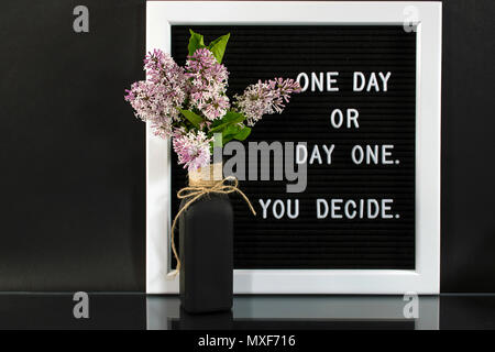 Bouquet lilla nero in bottiglia con preventivo motivazionale sulla bacheca Foto Stock