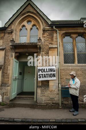 La gente va a poli nell'elezione generale 2017 foto di un conservatore teller sorge al di fuori della stazione di polling a Lacock Village Hall Foto Stock