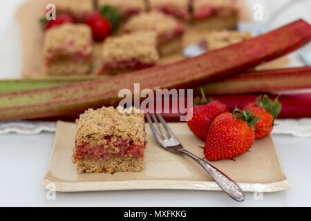 Fette di sani di rosso frutta estiva bar servita su un handmade piastra ceramica. Un delizioso pane appena sfornato dolci con fragole e rabarbaro. Foto Stock