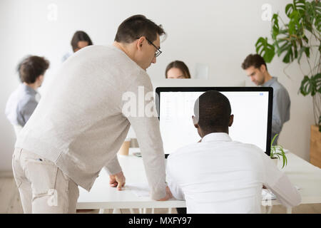 Senior mentor aiutando African American collega con PC Foto Stock