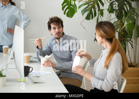 I colleghi di mangiare cibo asiatico dal box office durante il pranzo brea Foto Stock