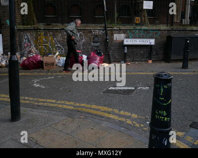 Un senzatetto uomo cammina passato i sacchetti di rifiuti al di fuori di St Leonards chiesa di Inghilterra, Shoreditch, Londra. Foto Stock