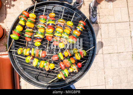 Per la cottura e Grill verdure - zucchine e pomodoro pepeer - gli spiedini su un barbecue all'aperto di un soleggiato weekend rilassante Foto Stock