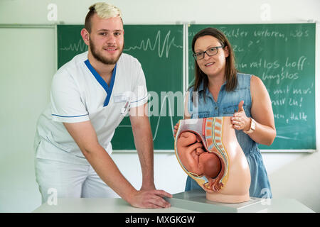 29 maggio 2018, Germania, Ansbach: Jasmin Treiber-Meyer, insegnante di ostetrica presso la clinica di Ansbach, spiega Konstantin Wroblewski, maschio ostetrica in formazione presso il Berufsfachschule für Hebammen und Entbindungspfleger am Klinikum Ansbach (lit. scuola professionale per levatrici e levatrici maschio a Ansbach clinica), l'anatomia femminile con l aiuto di un modello di plastica. Foto: Daniel Karmann/dpa Foto Stock