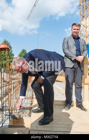 04 giugno 2018, Germania, Gardelegen: Rainer Robra (CDU), stato e ministro della cultura dello Stato della Sassonia Anhalt, la posa della prima pietra durante la cerimonia rivoluzionaria per visitatori e centro di documentazione. Dietro il candidato sta Kai Langer, direttore della Sassonia-Anhalt Memorials Foundation. Il memorial è situato presso il sito di Gardelegen massacro del 1945 e conmemorates tha 1016 campo di concentramento detenuti provenienti da diversi paesi europei che sono stati assassinati in Feldscheune, non lontano dalla città anseatica di Gardelegen, il 13 aprile 1945. Il nuovo edificio dovrebbe t Foto Stock