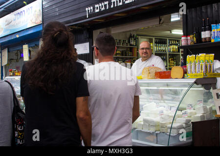 9 maggio 2018 un proprietario locale nei suoi locali con una selezione di formaggi caprini sul display al molto occupato Mahane Yehuda street market di Gerusalemme Foto Stock