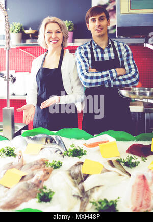 Donna matura e assistente maschio a lavorare nel negozio di pesce Foto Stock