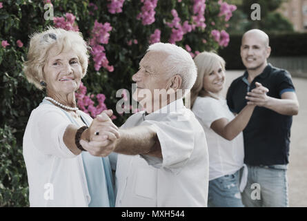 Felice allegro sorridente amici adulti dancing coppia danza in giardino Foto Stock