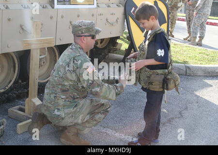 Un U.S. Soldato con la prima divisione di cavalleria fuori di Ft. Cappa, Tx. consente di montare l'ingranaggio di combattimento su un giovane bambino all'l'Accademia Militare degli Stati Uniti a West Point contro l'Università di Notre Dame del gioco del calcio al Alamodome a San Antonio nov. 12 2016. La prima divisione di cavalleria aveva una mostra al di fuori dell'Alamodome a promuovere esercito-legami civili. (U.S. La riserva di esercito foto di Spc. Ian Valley 345 PAD/rilasciato) Foto Stock