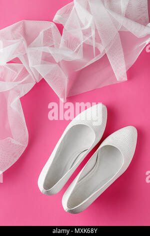 Bianco scarpe matrimonio con velo su sfondo rosa Foto Stock