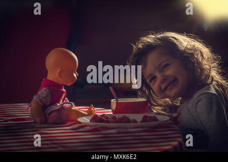 Carino bambina di mangiare fragole per la sua prima colazione al mattino. Foto Stock