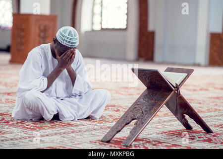 Musulmani africani uomo rendendo tradizionale preghiera a Dio indossando Dishdasha Foto Stock