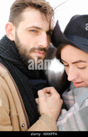 Close up ritratto dell'uomo abbracciando la donna che indossa un cappello e sciarpa. Foto Stock