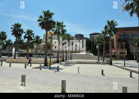 Street view da una piazza cittadina di Dürres, Albania. Le persone Camminare e stare in piedi intorno a parlare in distanza. Palloni da celebrazione. Acqua fou Foto Stock