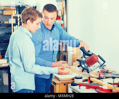 Ritratto di padre e figlio il taglio di tavolato in legno con tavolo visto nel posto di lavoro Foto Stock