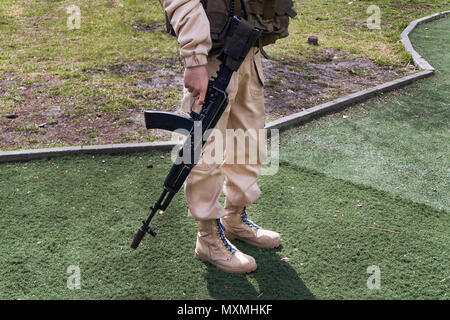 Militante islamico con un fucile. un soldato in una luce uniforme militare tenendo un kalashnikov contro lo sfondo di erba Foto Stock