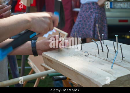 L'uomo martellare un chiodo in un blocco di legno duro che ha causato numerosi altri chiodi a piegarsi in una chiusura delle mani Foto Stock