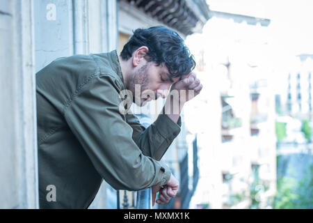 Close up ritratto della triste e depresso uomo guardando fuori dalla finestra su un balcone di casa soffre di depressione e di abbattimento lonely in salute mentale concep Foto Stock