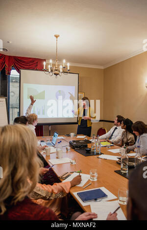 Vista posteriore di una sala conferenza riempito con la gente di affari. Un imprenditore è alzando la mano per chiedere il presentatore di una domanda. Foto Stock