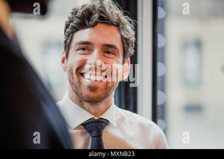 Close-up, oltre la spalla di un imprenditore alla ricerca e sorridente in un irriconoscibile persona. Foto Stock