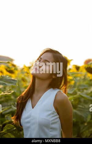 Giovane bella donna asiatica con gli occhi chiusi nel campo di blo Foto Stock