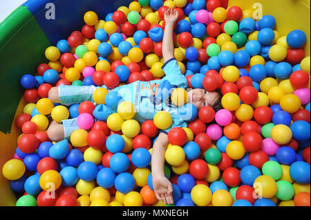 Lione (sud-est della Francia). Bambino sdraiato con le braccia aperte in una sfera colorata pit modello di rilascio o Foto Stock