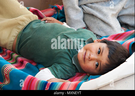 Un giovane bambino peruviano posa su un tessuto colorato coperta in Cusco Peru Sud America Foto Stock