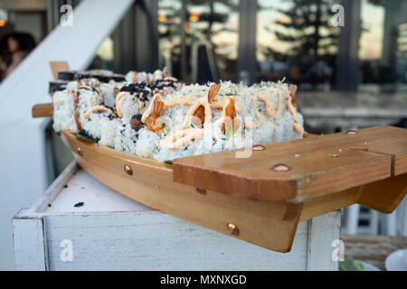 Crostini: assortimento di sushi rotoli essendo servita su una barca di legno Foto Stock