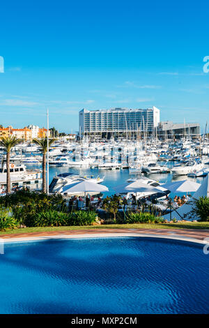 Il lungomare pieno di famiglie accanto alla marina presso il quartiere alla moda di località di VilaMoura nel sud della regione portoghese dell'Algarve. Luxury Hotel Tivoli visibile Foto Stock