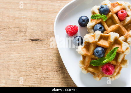 Tradizionale cialde belghe con mirtilli e lamponi su un tavolo di legno. Vista dall'alto. Copyspace Foto Stock