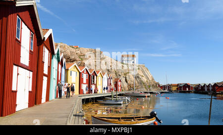 Smogen, Svezia - 19 Maggio 2018: documentario di viaggio della vita di tutti i giorni e il luogo. La gente che camminava su un molo con colorati boathouses in un pomeriggio soleggiato. Foto Stock