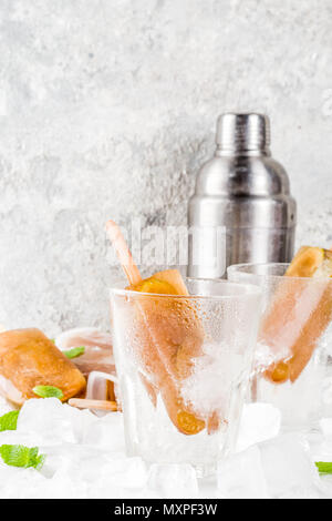 Congelati bevande rinfrescanti, cocktail estivi popsicles ricetta, cuba libre, dolce freddo il tè o il caffè con ghiaccio, lime e foglie di menta su marmo bianco backg Foto Stock