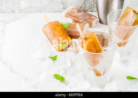 Congelati bevande rinfrescanti, cocktail estivi popsicles ricetta, cuba libre, dolce freddo il tè o il caffè con ghiaccio, lime e foglie di menta su marmo bianco backg Foto Stock