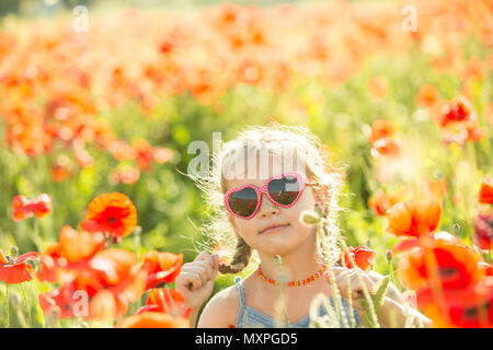 Sorridente ragazza piuttosto su una passeggiata al campo di papavero. Foto di stile di vita Foto Stock