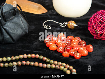 Rune arancione per la divinazione con gli attributi di magica sul tavolo Foto Stock