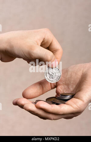 Mano dando una moneta ad un altra persona, primo piano Foto Stock