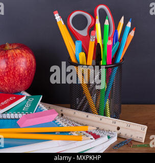 Primo piano di un assortimento di forniture scolastiche su un sfondo lavagna Foto Stock