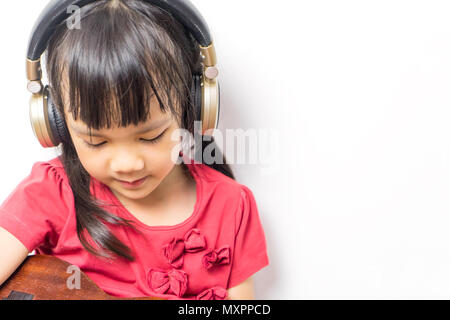 Ragazza asiatica sta suonando la chitarra di musica con le cuffie su sfondo bianco. Foto Stock