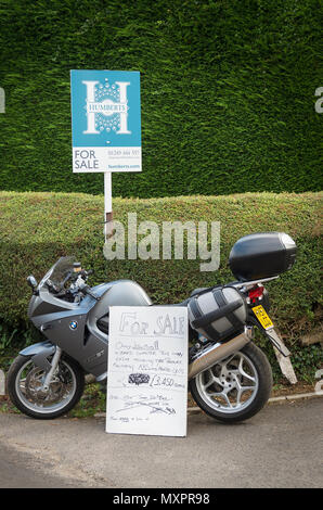 Due articoli per la vendita. Casa e BMW moderno ciclo motore promosso al di fuori della proprietà sul ciglio della strada in Inghilterra, Regno Unito Foto Stock