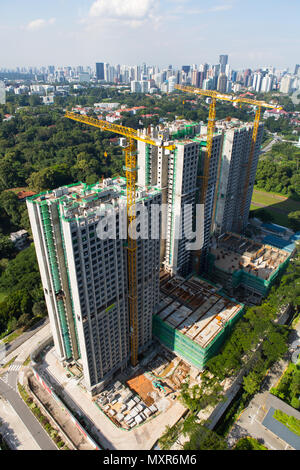 Una vista verticale di tre gru a torre coinvolte nella costruzione di appartamenti a Singapore. Foto Stock