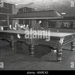 1948, storico, giovani giocando una partita di biliardo o snooker in un club biliardo, su un full-size tabella, Inghilterra, Regno Unito. In questa epoca, biliardi e/o snooker è stata una popolare le attività per il tempo libero ma il passatempo aveva limitato ricorso al di fuori di quelli che hanno giocato. Snooker, il cosiddetto 'cue sport', originati tra British ufficiali dell'esercito di stanza in India nel tardo XIX secolo. Foto Stock