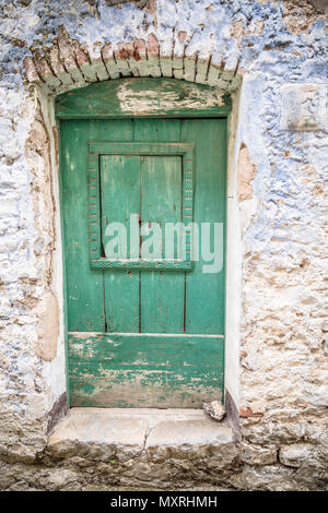 Vecchio blu verdastro porta di legno e muro eroso. Sportello anteriore. Ingresso alla casa Foto Stock