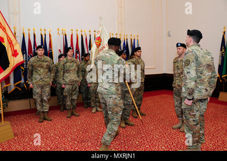 Il cap. Olufemi O. Apata, centro, comandante in entrata della sede centrale e sede di distacco, U.S. Presidio militare di Ansbach, passa la sua unità guidon torna a Sgt. 1. Classe Alvin bianco, distacco sergente, durante un cambio del comando cerimonia per l'unità 6 dicembre 2016, presso il Von Steuben centro comunitario in Ansbach, Germania. (U.S. Esercito Foto di Georgios Moumoulidis, TSC Ansbach) Foto Stock