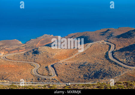 Strade strette, un sacco di giri, paesaggio secco come si guida verso il basso per coste meridionali di creta.Vista mozzafiato blu infinito del mare Libico Foto Stock