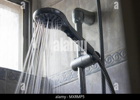 Alta pressione di spruzzatura di acqua corrente dal versamento di una doccia mobile. Foto Stock