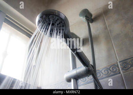 Una testa di doccia e di un flusso di acqua versando da esso in un modello di spruzzatura. Foto Stock