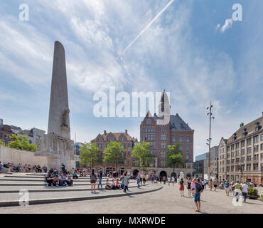 AMSTERDAM, Paesi Bassi - 27 Maggio: (nota del redattore: immagine è stata migliorate digitalmente.) i turisti prendere un po' di riposo accanto al monumento nazionale (in olandese: Nationaal Monument op de Dam) in Piazza Dam il 27 maggio 2018 a Amsterdam, Paesi Bassi. Questo monumento consente alle persone di commemorare le vittime della Seconda Guerra Mondiale. Foto Stock