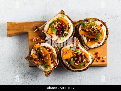 Snack vari tipi di pane con hummus e zucca cotta su una scheda che serve con pesto di rucola. i semi di melograno e pinoli. cibo sano Foto Stock